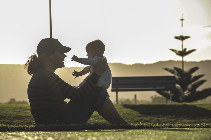 A mom and her little baby play together outside.