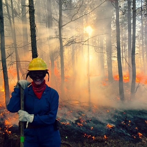 Erin smiles triumphantly as a successful burn blazes behind her.