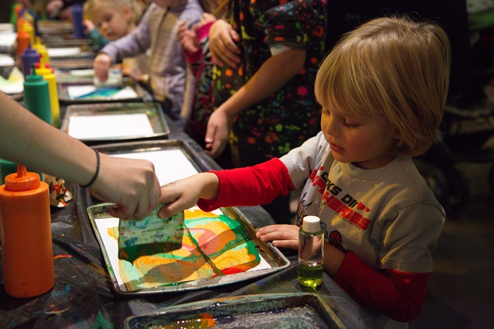 Child uses colorful paints to make a dazzling artwork.