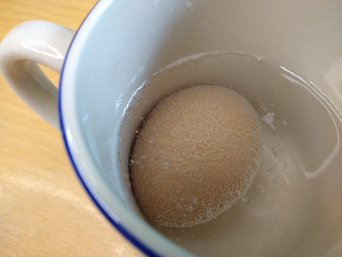 An egg sits in a cup of vinegar.