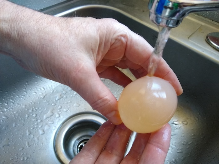 The egg is rinsed under water.