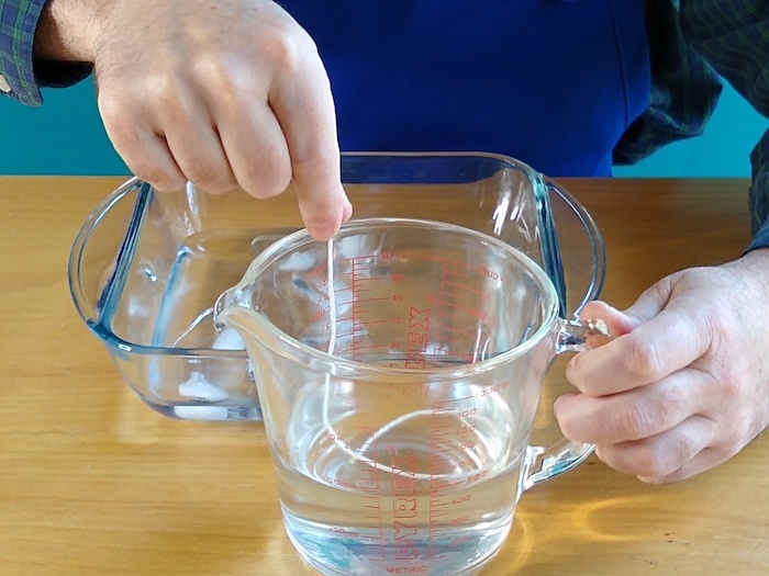 A string is submerged into a different cup of water.
