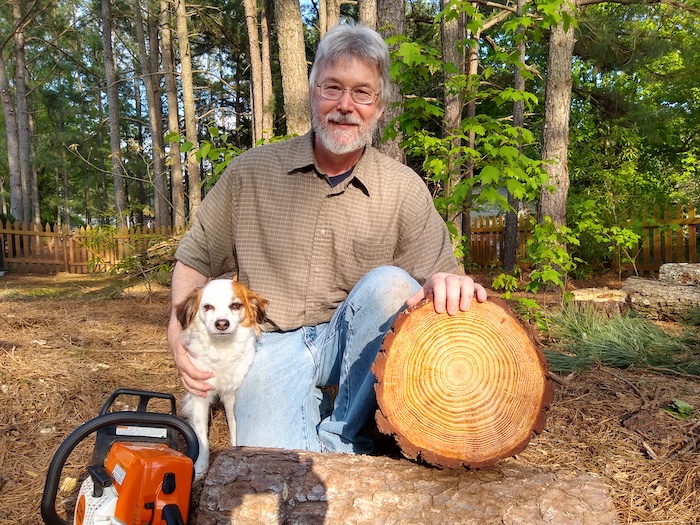 Bob stands next to a cut down tree.