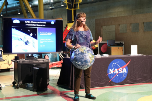 A woman from NASA giving a presentation with an Earth beach ball