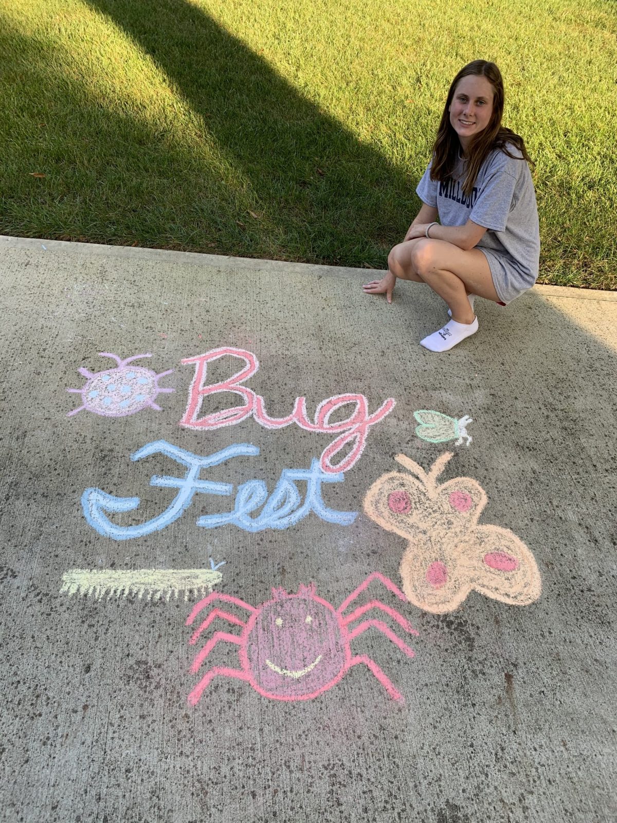 a young woman by a cursive bugfest and an assortment of chalk bugs