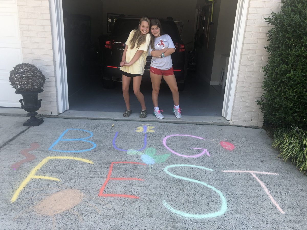 Two girls with BugFest in chalk on the driveway