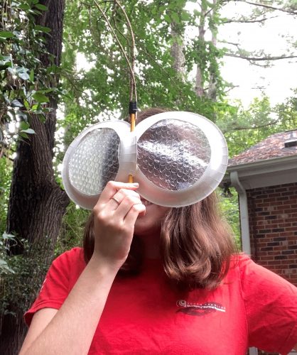 A woman holding homemade fly eyes up to her face