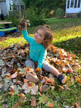 Child playing in a pile of leaves.