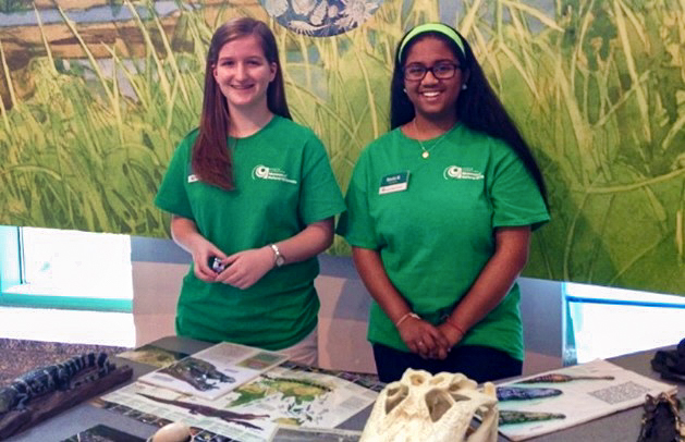 Two teenagers volunteering at a Museum table.