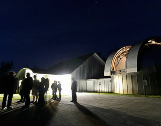 People standing outside an observatory at night