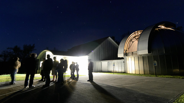 People standing outside an observatory at night
