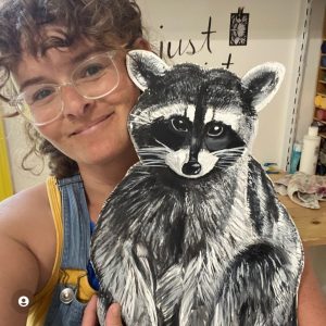 Artist Bess Taylor with a handpainted raccoon