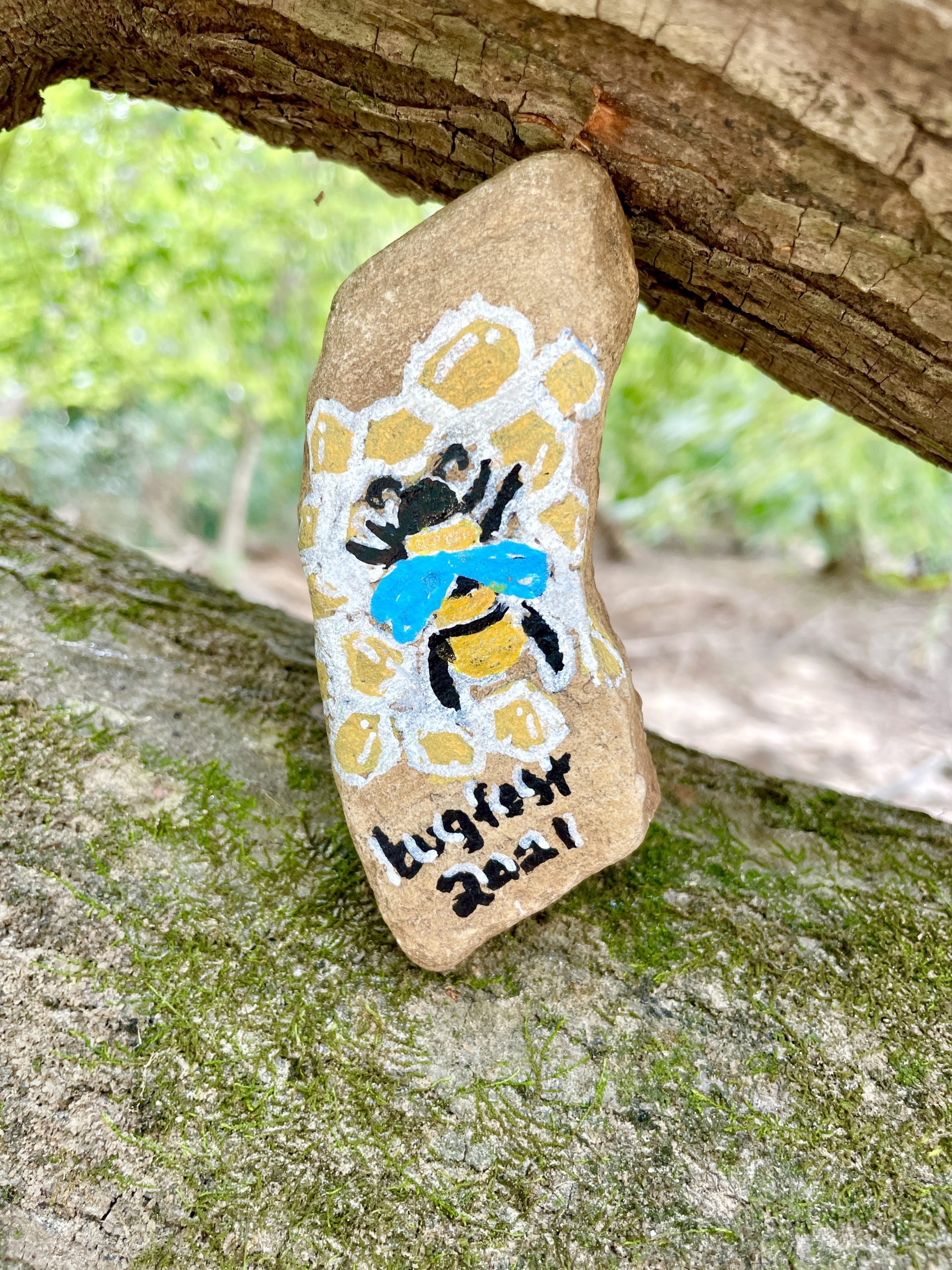 a bee and honeycomb painted on a rock