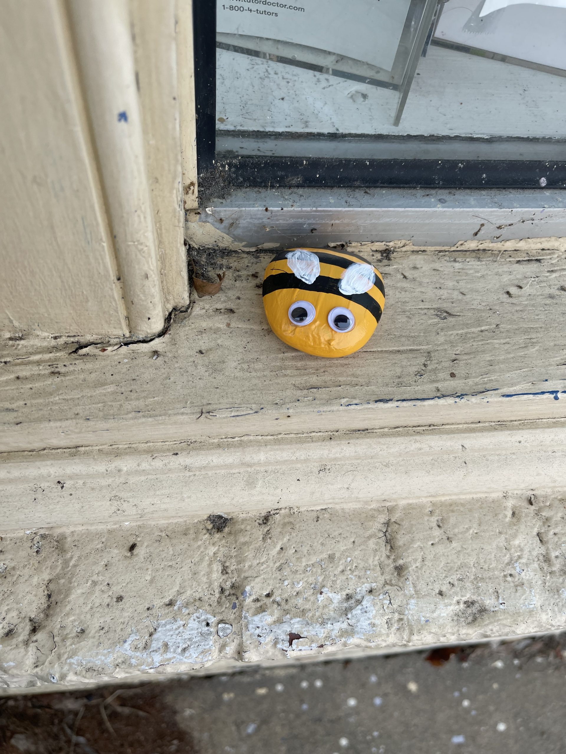A bee painted on a rock on a windowsill