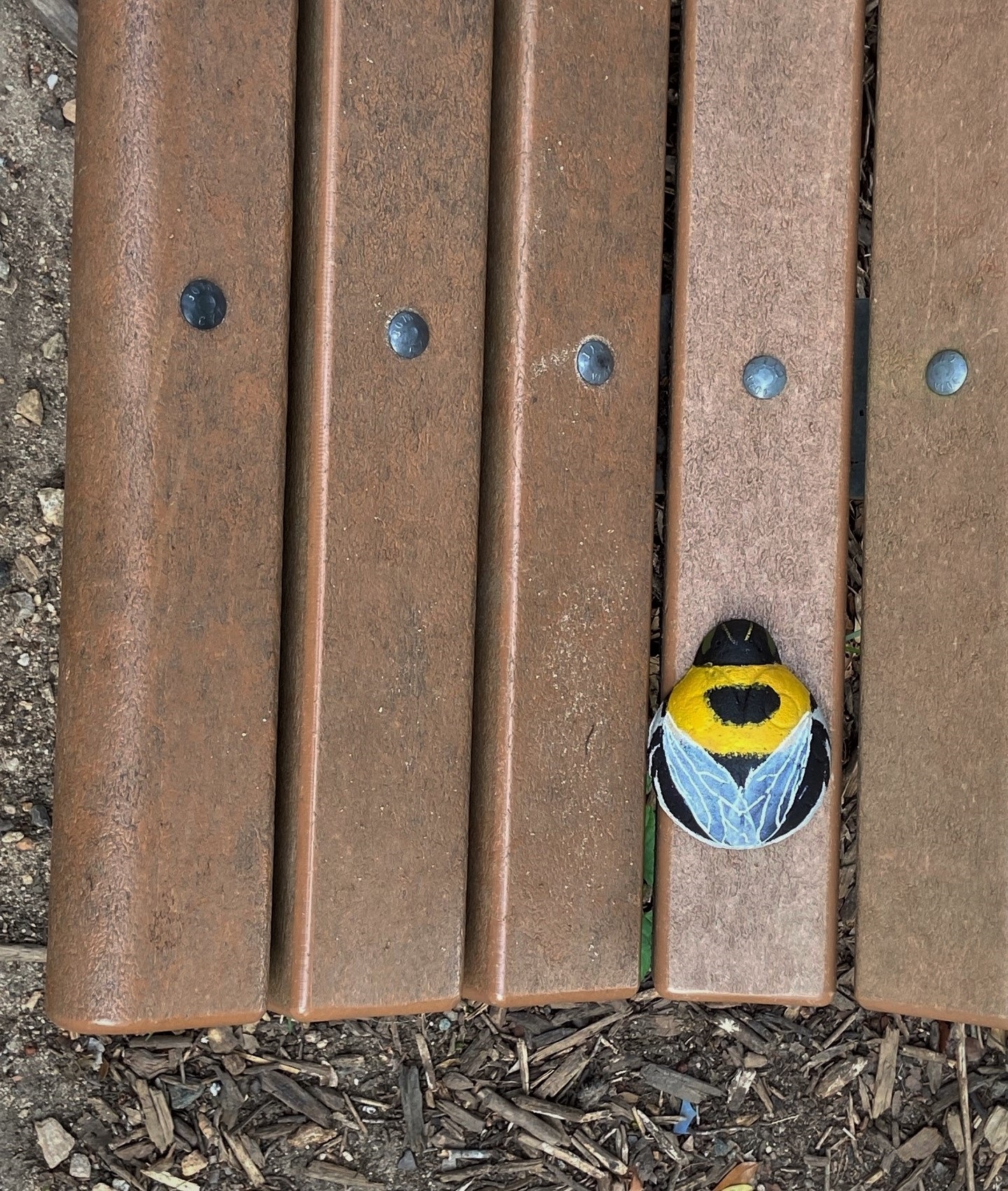 a bee painted on a rock on a bench