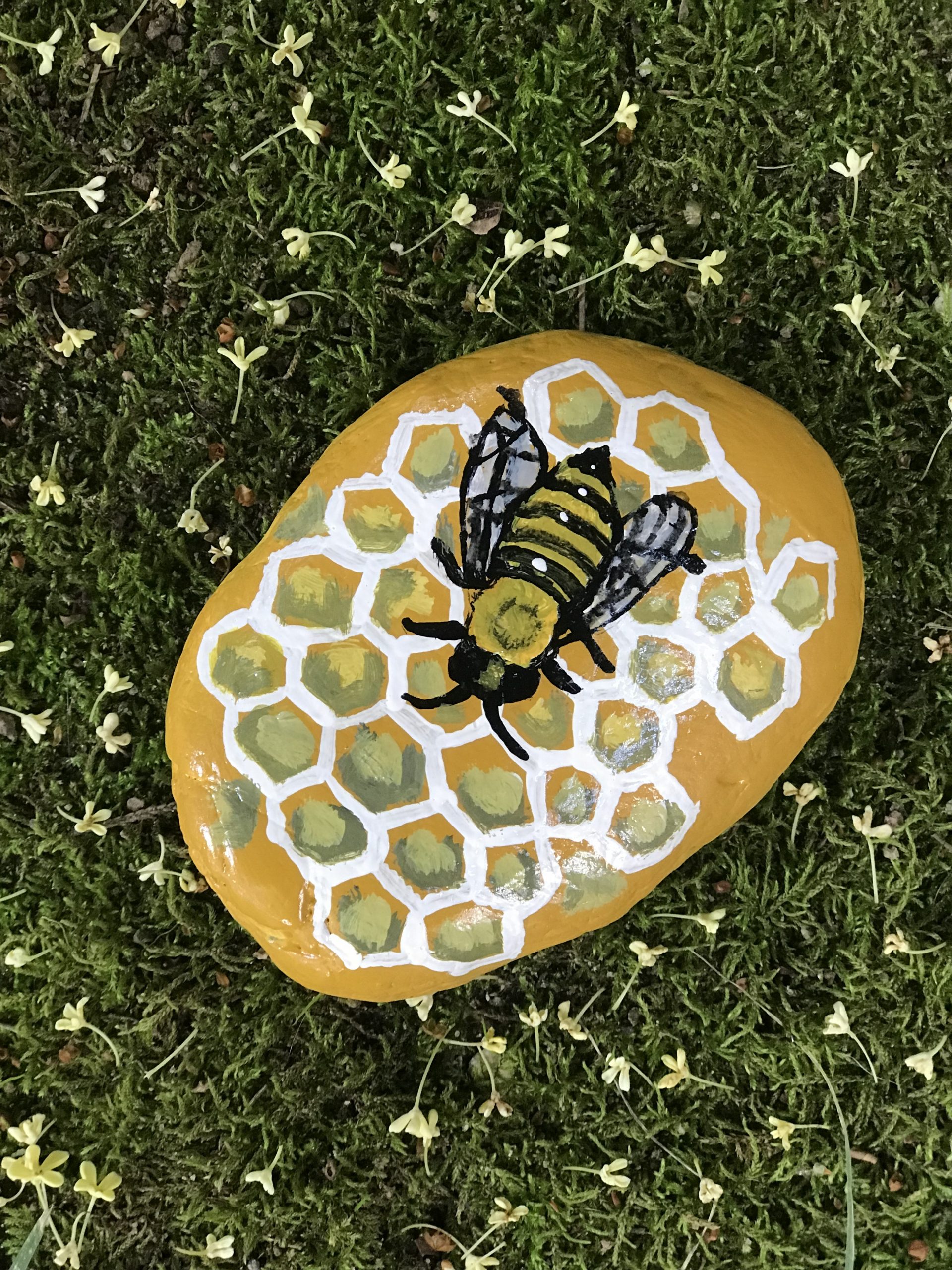A bee and honeycomb painted on a rock