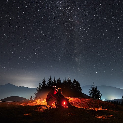 Two people sitting by a campfire