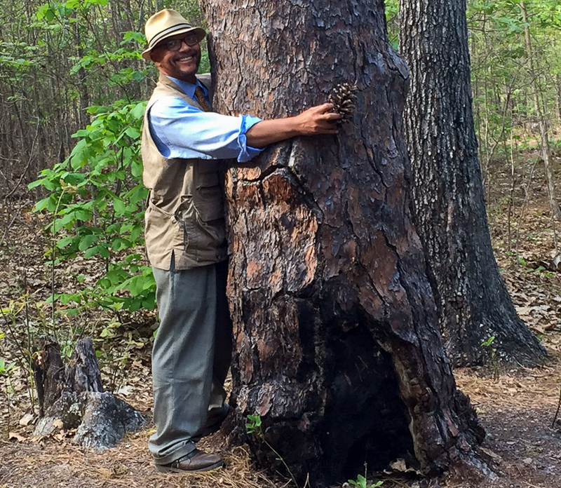 Earl L. Ijames hugging a pine tree.