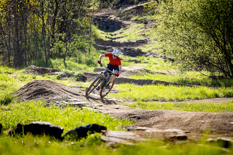 Mountain biker rounds a corner on a rocky trail.