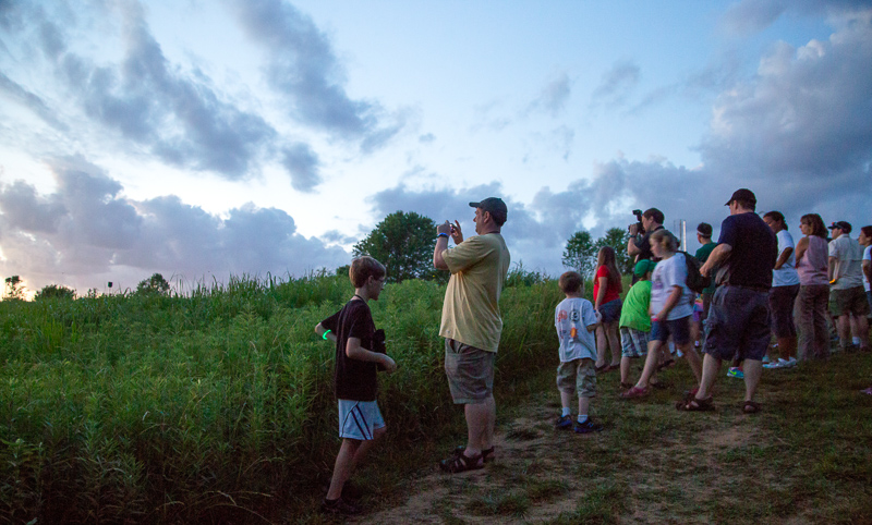 A group of Museum members walks along the edge of the prairie at Family Safari Night.