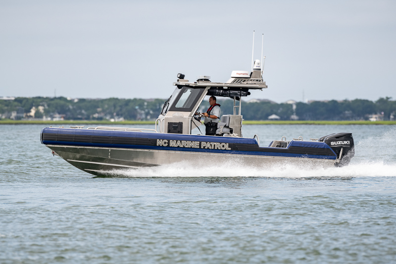 A boat labeled "NC Marine Patrol" speeds along in the water.
