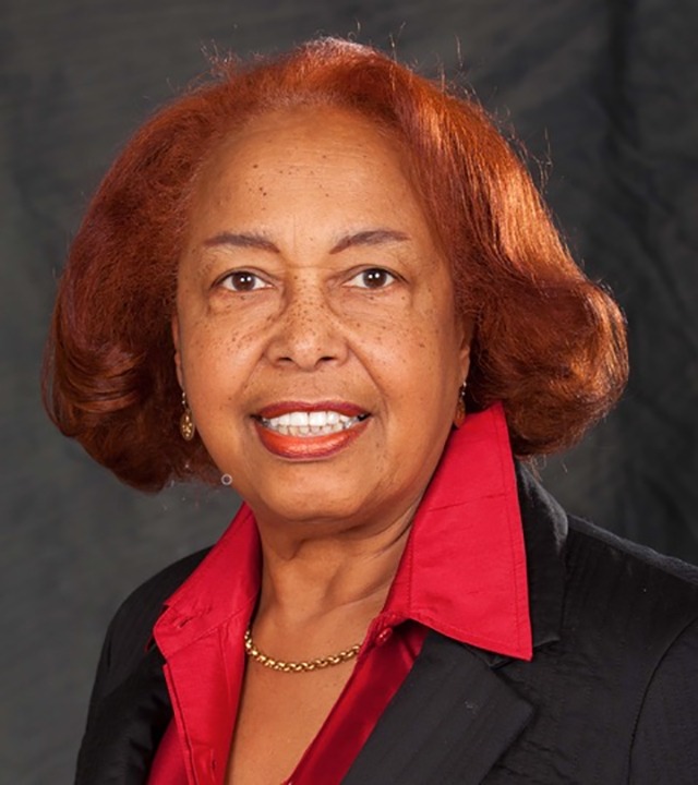 Dr. Patricia Bath, dressed in a black suit and red shirt.