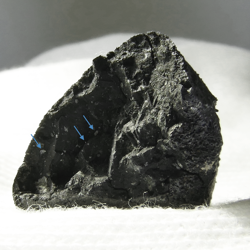 Interior face of Tarda showing bits of nickel and iron, white against the black matrix [blue arrows].