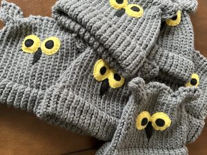 Gray knitted owl hats with yellow eyes.