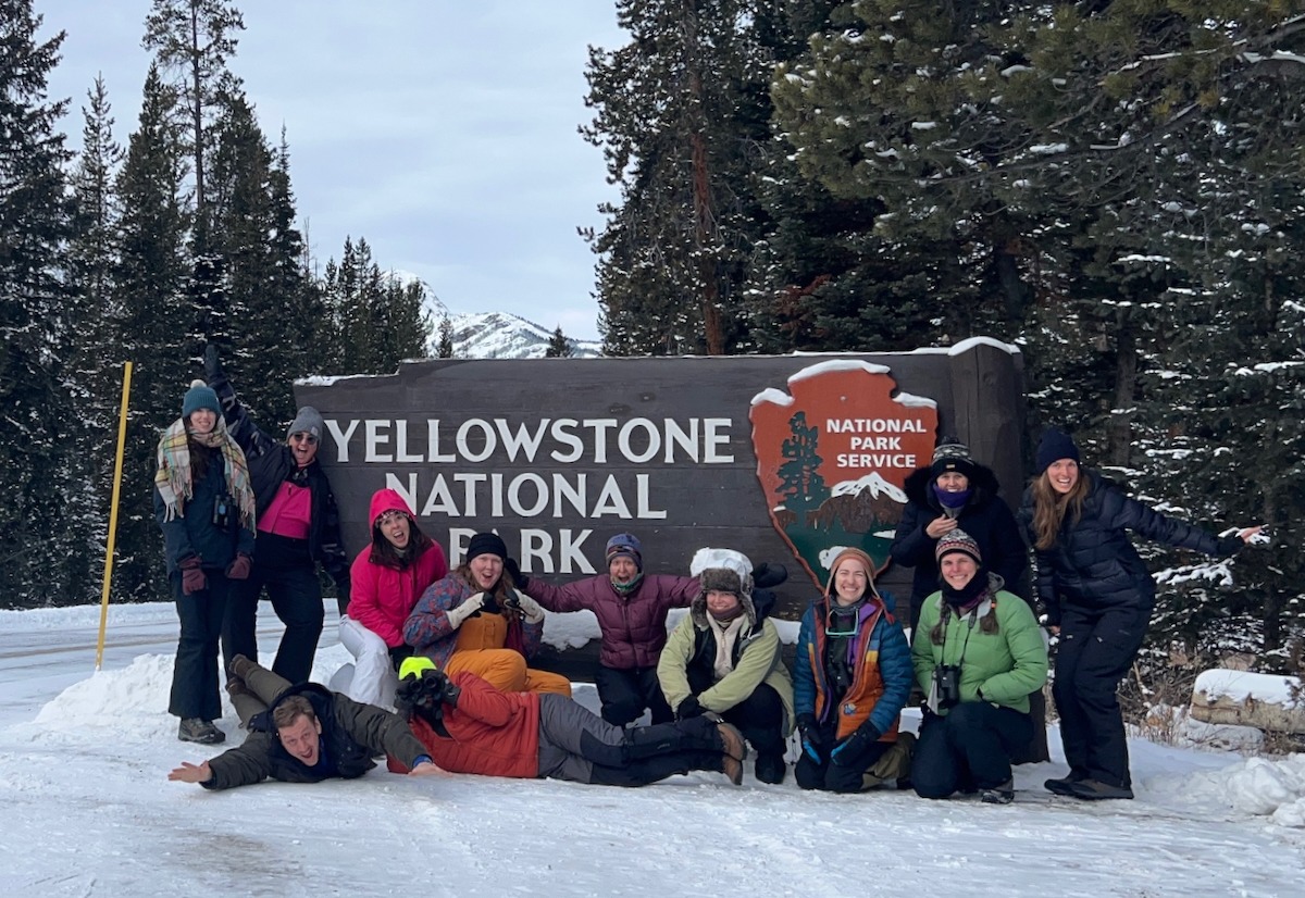 The 2024 Yellowstone in Winter Institute team in front of one of the park entrance signs.