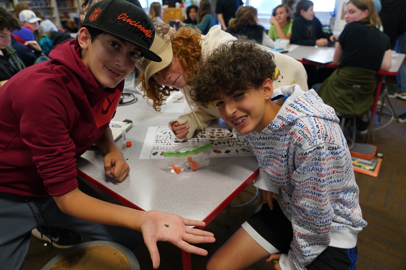 Middle school boys showing off a microfossil they found during a Cretaceous Creatures class.