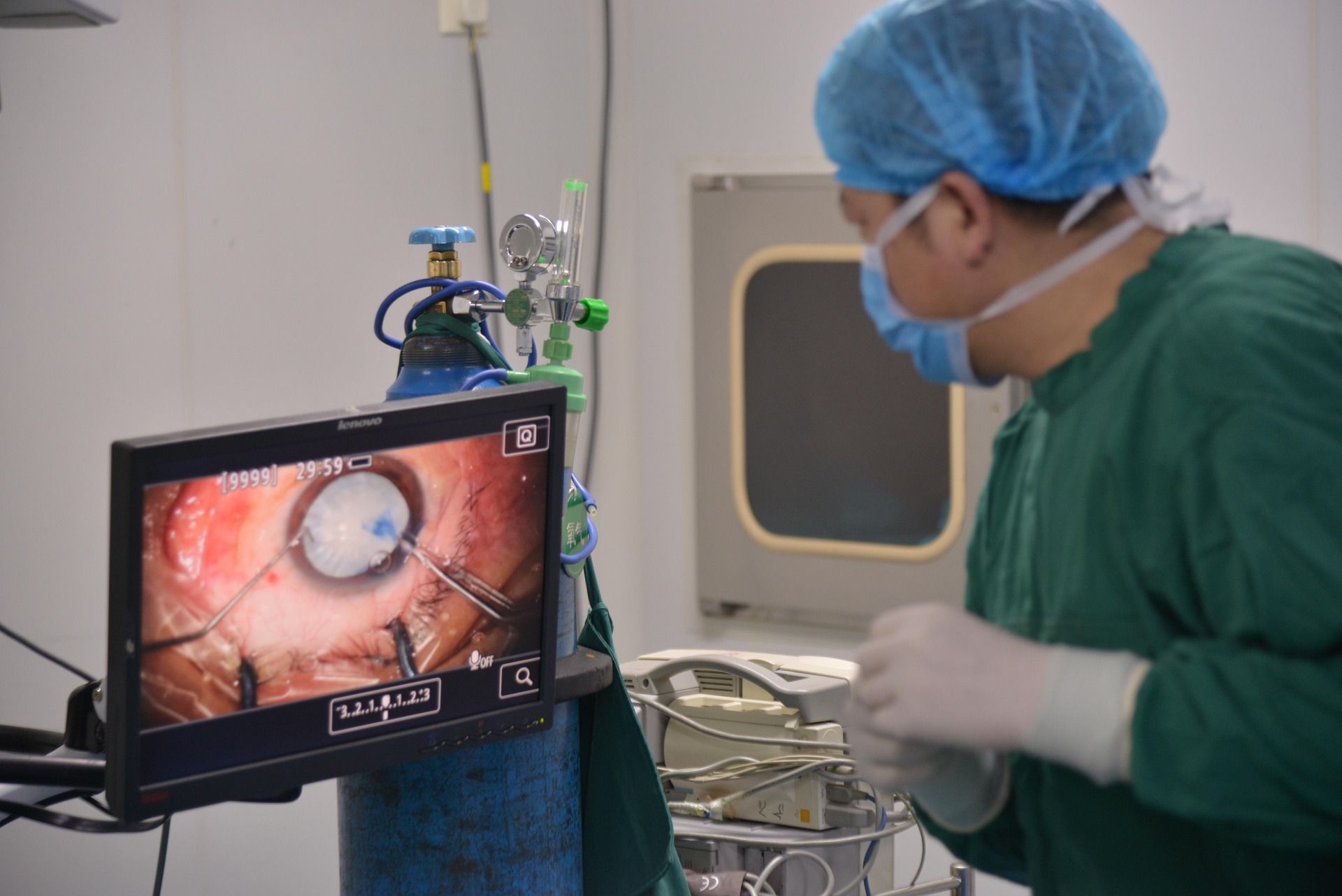 person in medical dress conduct robotic surgery while watching a screen